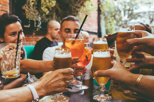 Multiple people cheersing alcoholic drinks at a venue with people in the background