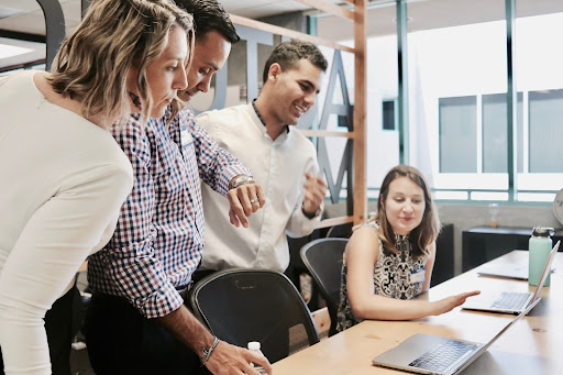 People sitting and standing looking at a laptop