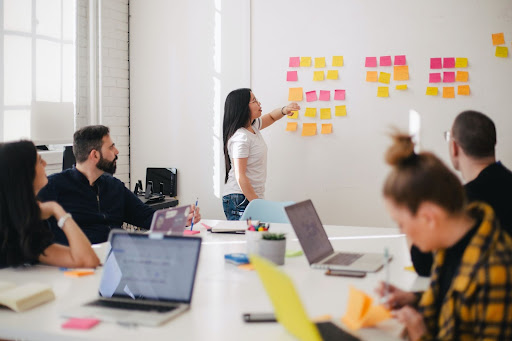 People sitting at a desk in front of a whiteboard